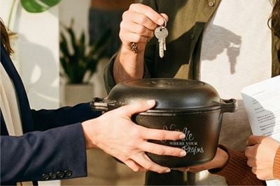 New homeowners receiving a Lodge cast iron Dutch oven as a housewarming gift.