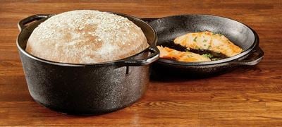 Lodge Dutch oven lid used as a cast iron skillet for searing salmon next to freshly baked bread.