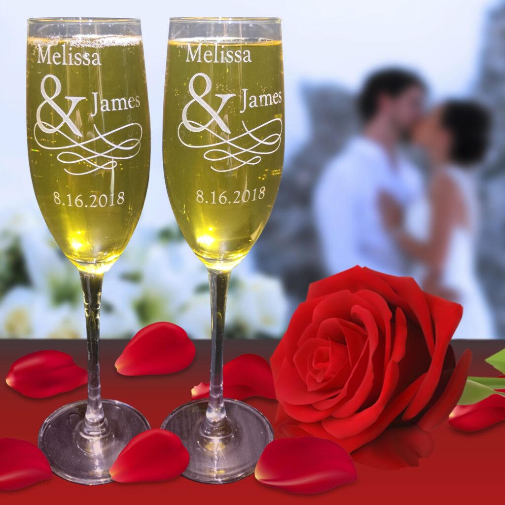 two engraved wine glasses on table next to rose 