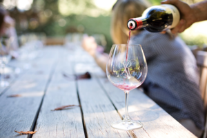 engraved wine glass on picnic table with red wine pouring into it