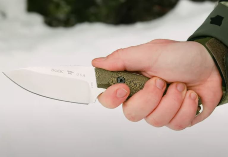 Laser engraved Buck hunting knife held by man with snow background