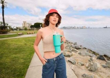 Woman standing outside holding a teal Stanley Quencher
