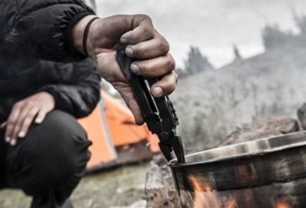 Woman holding Gerber MP600 pliers for hot pan while camping