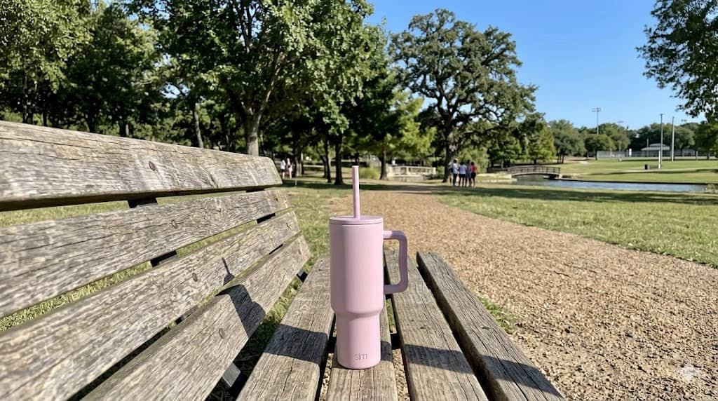 Pink Simple Modern tumbler on a park bench under a clear sky.